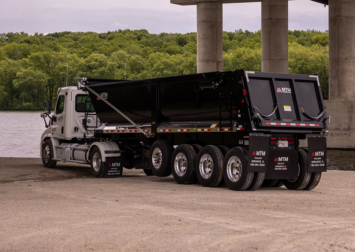 black quad end-dump trailer under a bridge