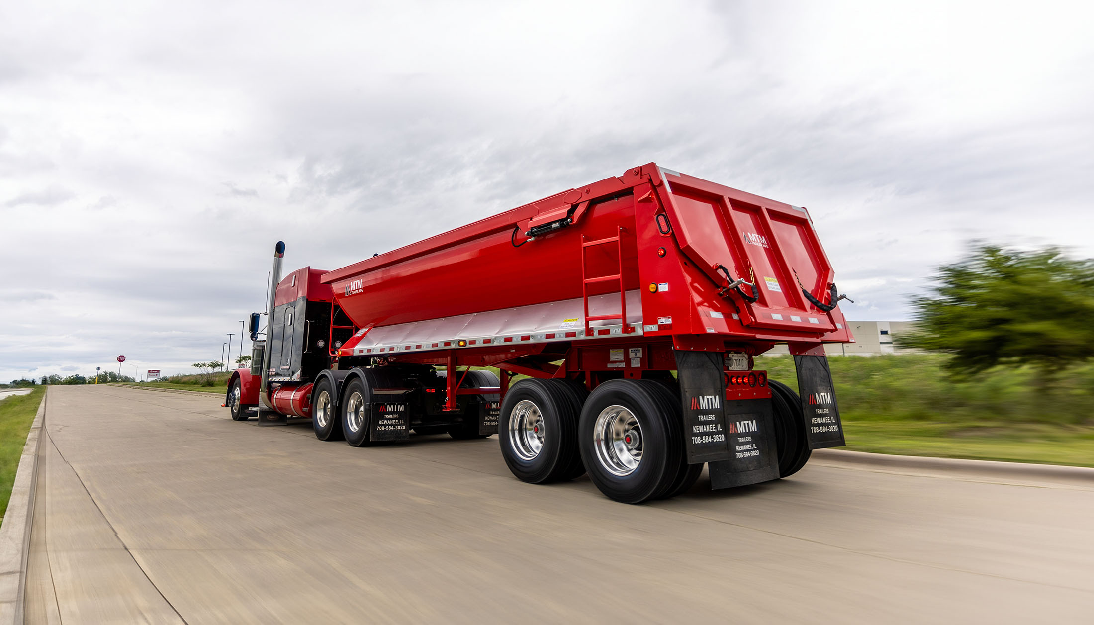 Red quarter-frame end-dump trailer on the road