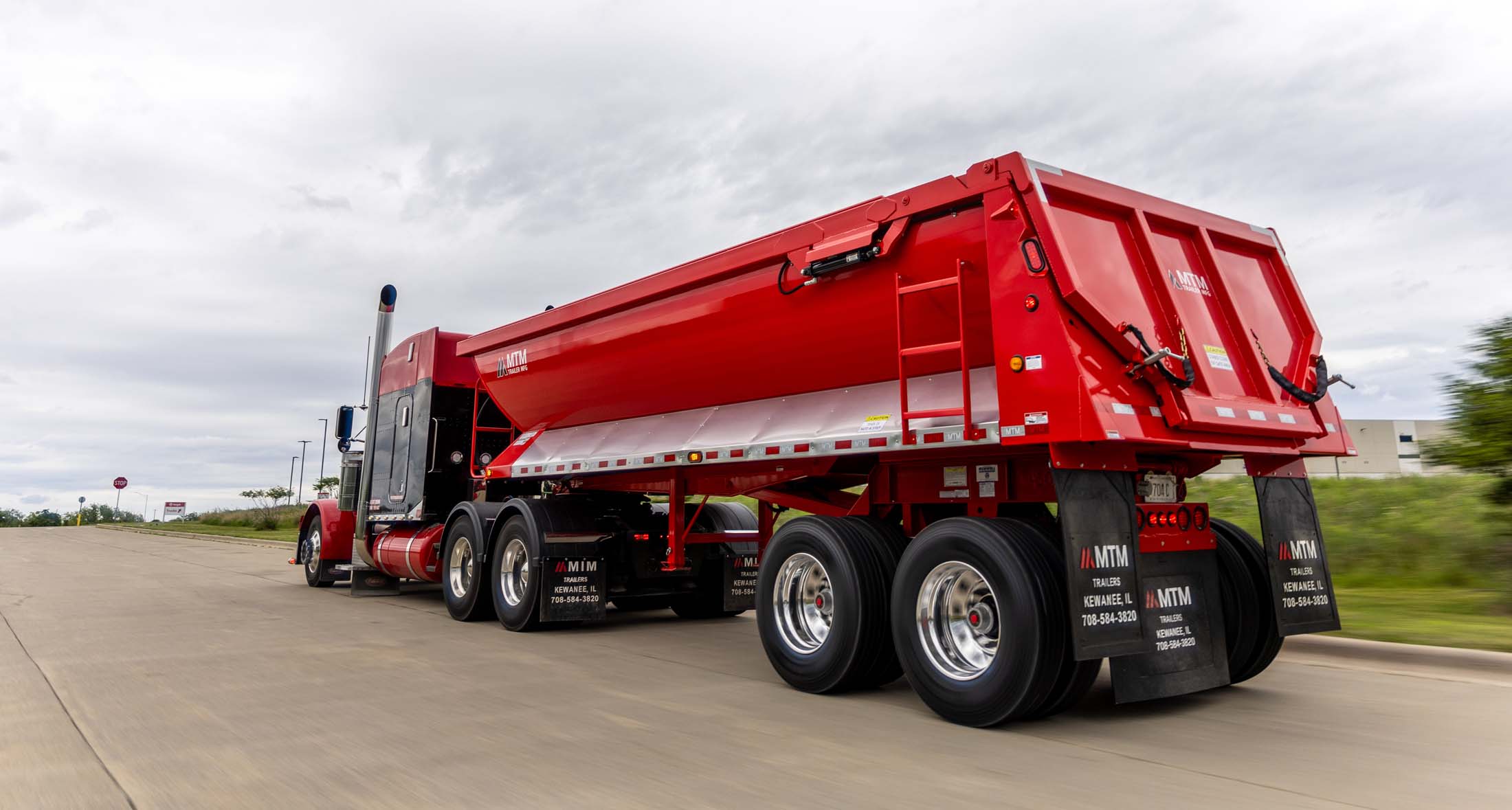Red quarter-frame end-dump trailer on the road