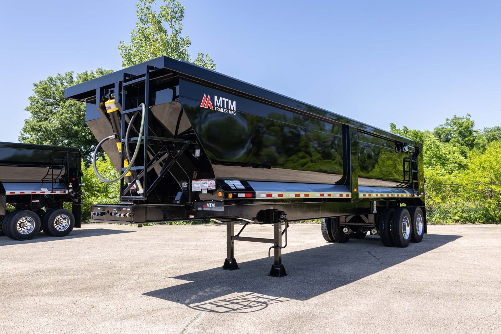black heavy-duty full-frame MTM end-dump trailer side view
