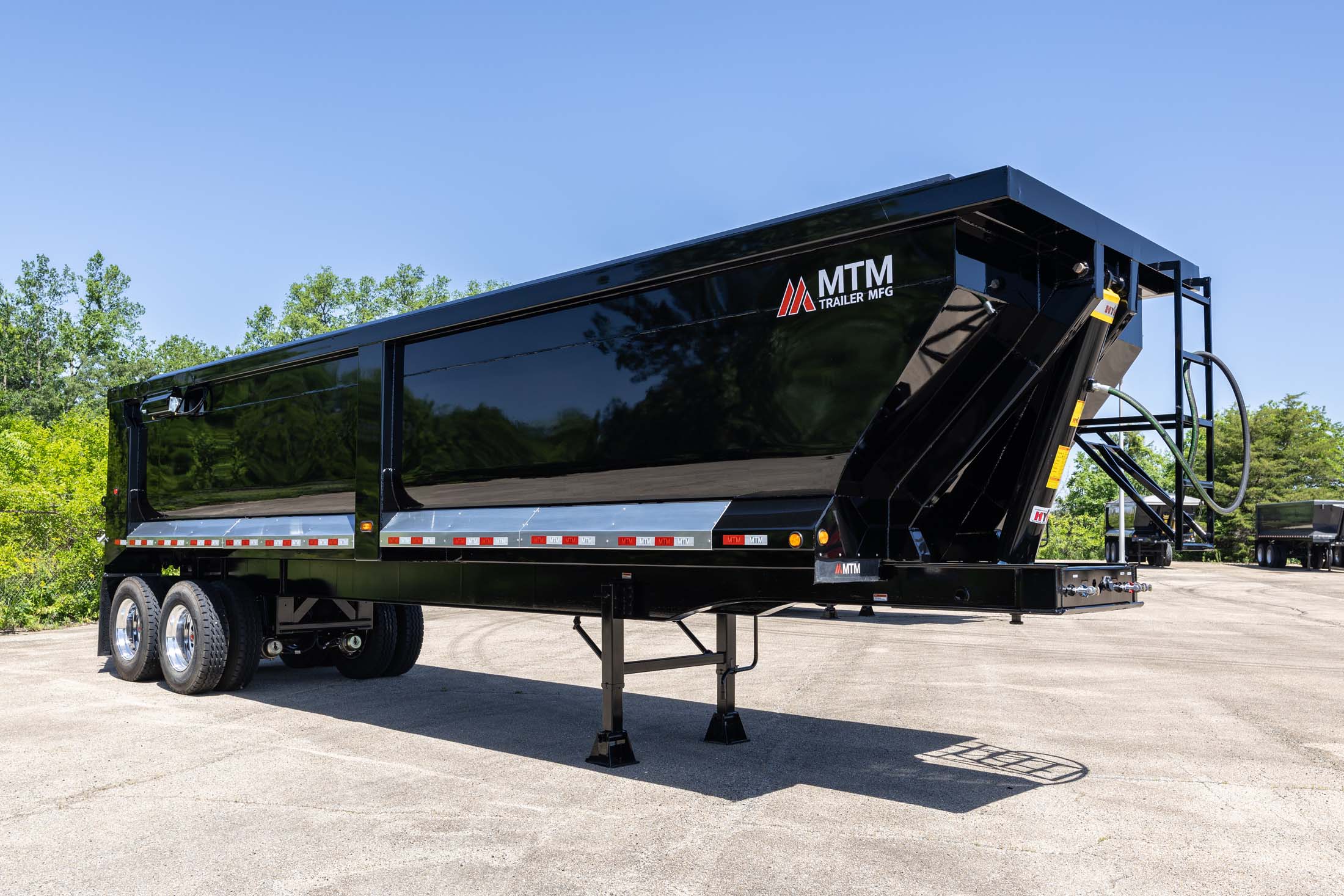 black heavy-duty full-frame MTM end-dump trailer side view