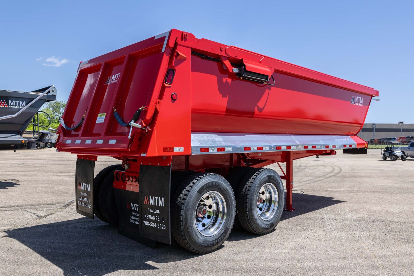 Red MTM quarter-frame end-dump trailer, view of the side