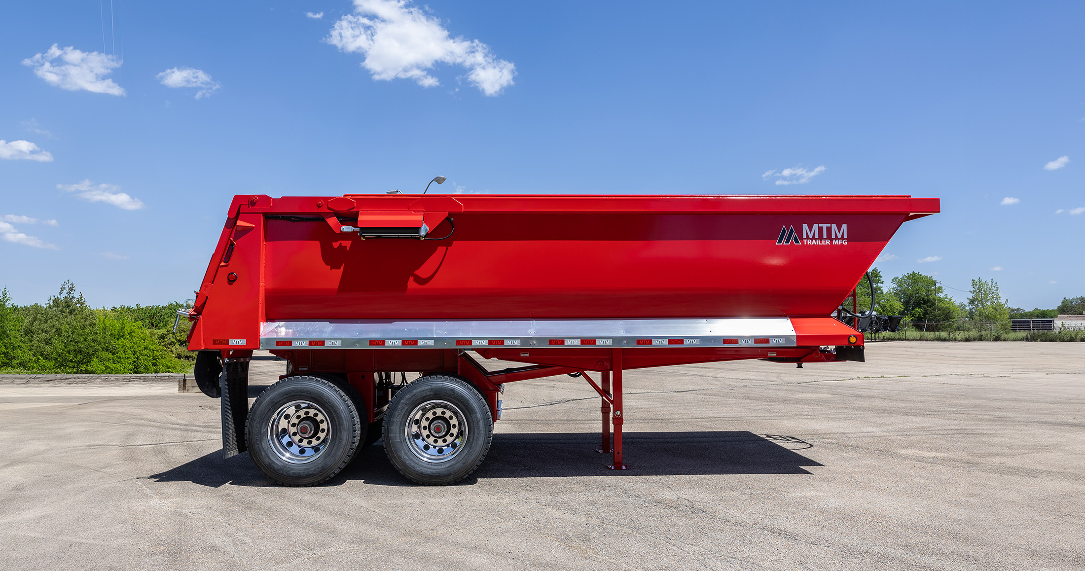 Red MTM quarter-frame end-dump trailer, side view