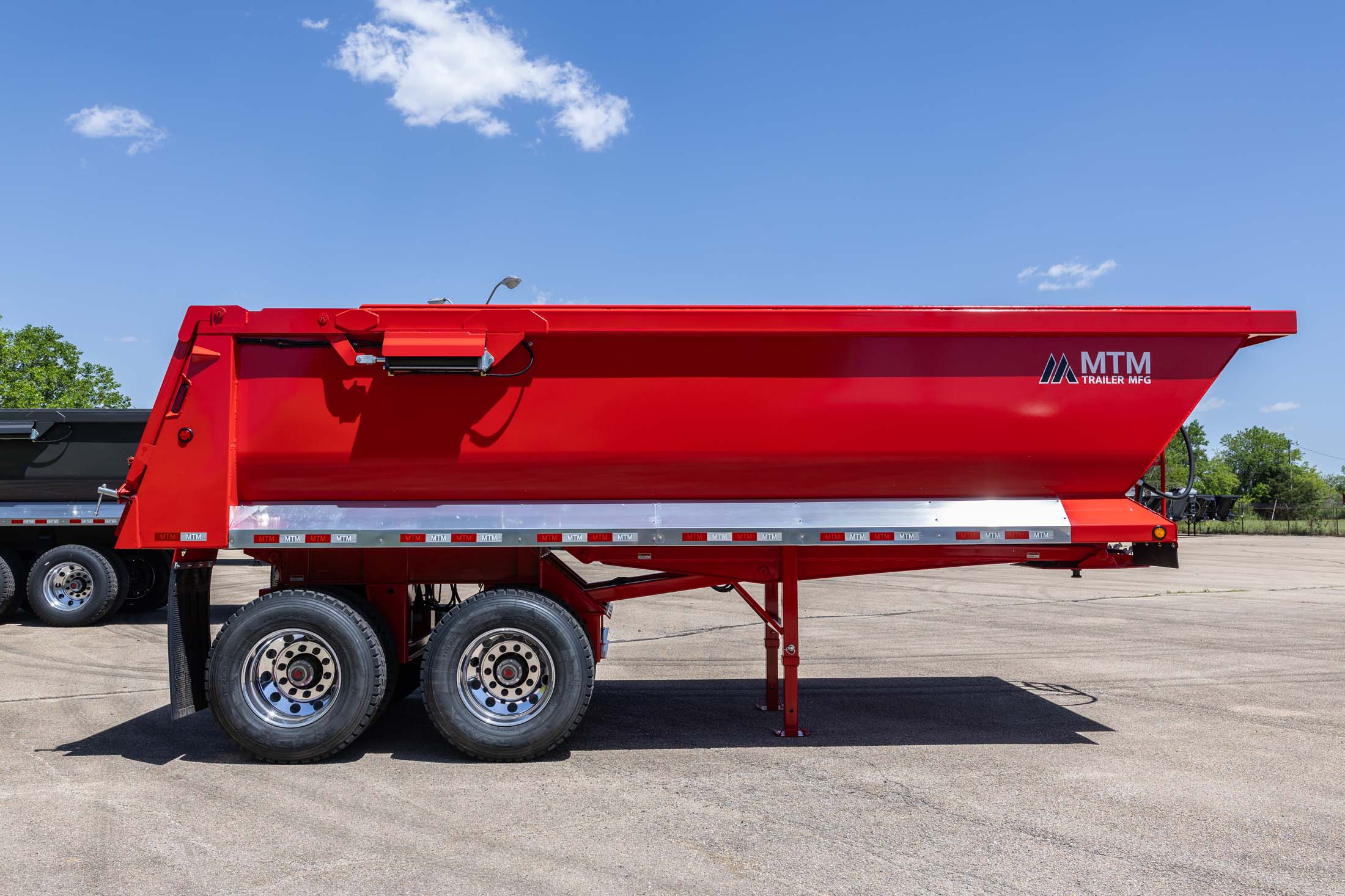 Red MTM quarter-frame end-dump trailer, side view