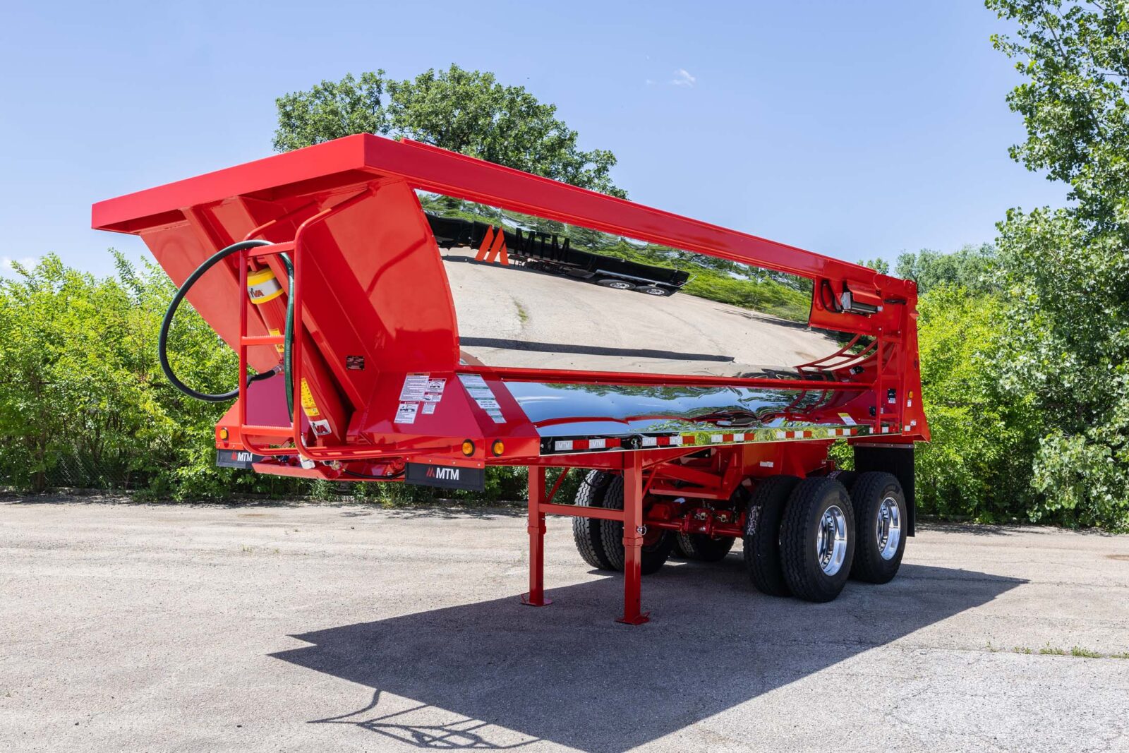 Red MTM quarter-frame end-dump trailer with chrome finish, front view