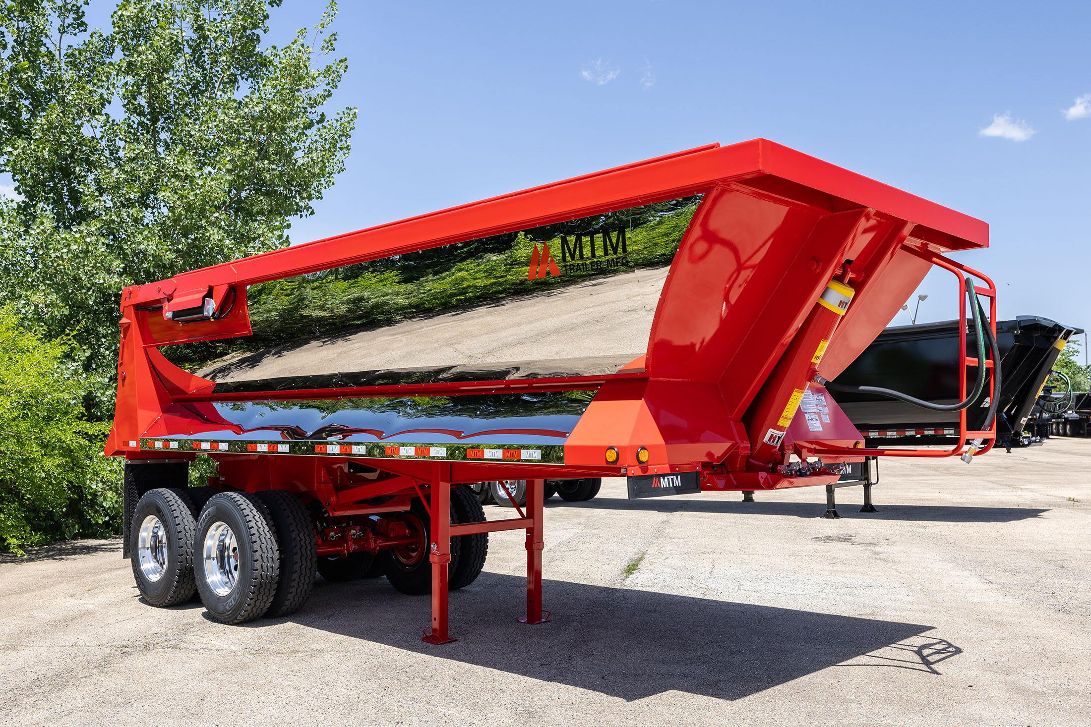 Red MTM quarter-frame end-dump trailer with chrome finish, side view