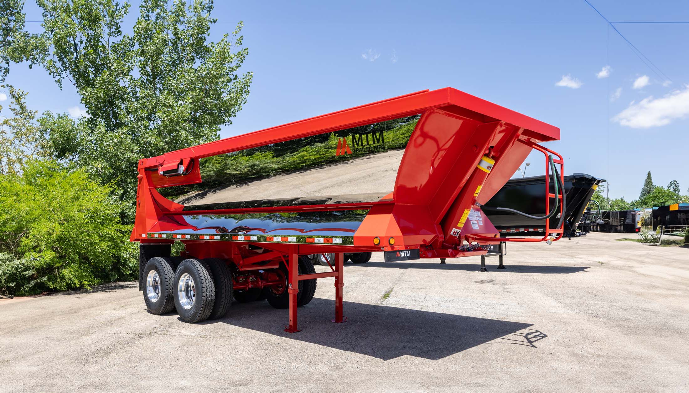 Red MTM quarter-frame end-dump trailer with chrome finish, side view