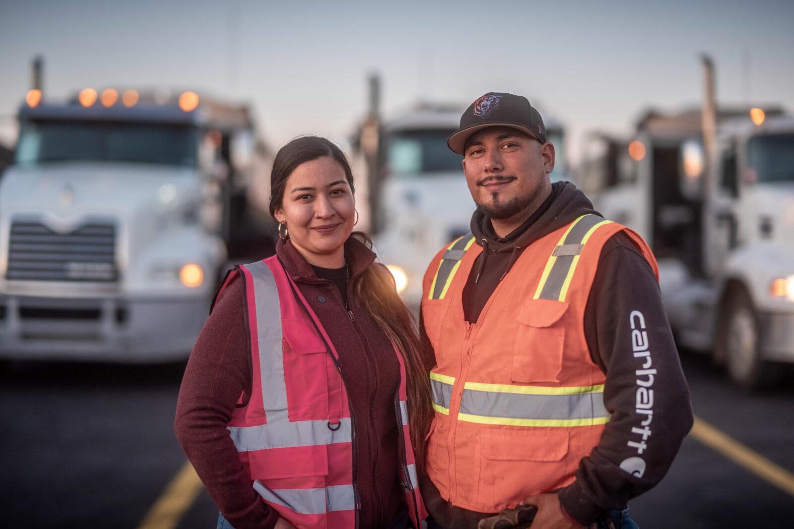woman and man owner-operator couple smiling and standing in front of their fleet