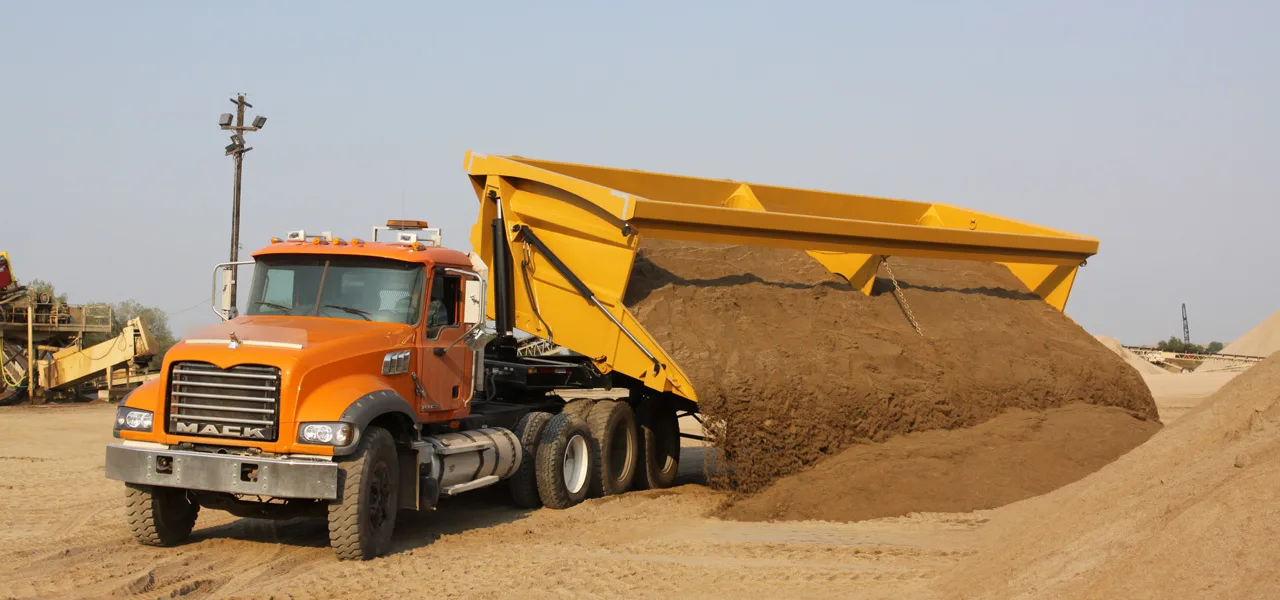 yellow side-dump trailer dumping
