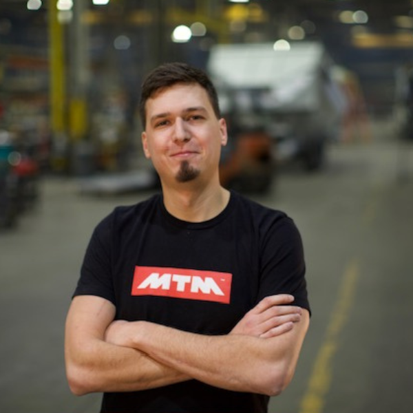Man in an MTM shirt standing in front of an end-dump trailer